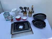 Full lot displayed with roasting pans, baking sheet, pie plate, bowls, utensils, and travel mug plus decorative box