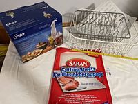 Oster hand blender with chopper and blending cup in original box, Saran cutting sheets opened but resealed, metal and plastic dish drainers.