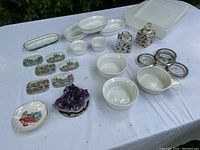 Overview photo showing white ceramic dishes and bowls, decorative trinket boxes, scenic coasters, and amethyst cluster.