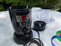 Magic Bullet single shot blender base, blending cup, and blade attachment in black.