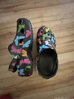 Side and top angle showing colorful butterfly printed platform Crocs, black base, ventilation holes and adjustable strap.