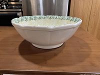 Side view showing white ceramic bowl with scalloped edge on wooden table