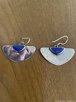 Pair of sterling silver earrings with bright blue lapis lazuli stones on wooden surface