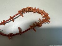 Close-up image of the natural coral choker necklace showing irregular coral chip beads on a string.