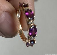 Close-up photo of the ring showing the side view of the oval rhodolite garnets and diamond accents with the 14k rose gold setting visible.