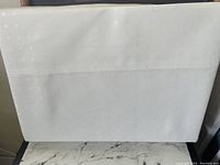 Photo showing a white queen size sheet with subtle woven checkered pattern, laid flat to display fabric texture.