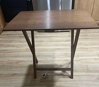 Photo of the table showing the full top surface and base construction on a wood floor.