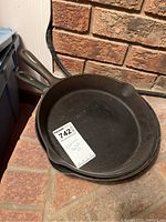 Two cast iron skillets stacked, showing their size and condition with a label on top skillet.