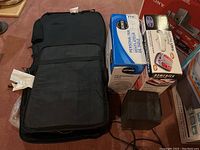 Overview photo showing the Homedics Foot Pro Ultra foot massager in black, the Likewise personal fan box, Duracraft heater, and two heating/massaging chair pads.
