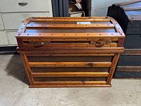 Front view of rectangular wooden trunk with metal details and loose lid
