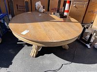 Top and side view of the large round solid oak coffee table with visible scratches and scuffs on the surface.