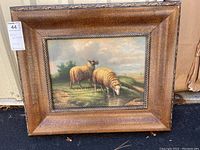 Full view of the framed original art painting showing two sheep in a natural setting, with a brown textured wooden frame.