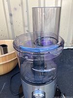 Small electric food processor or chopper with clear plastic bowl and silver-toned metallic base, black power cord visible