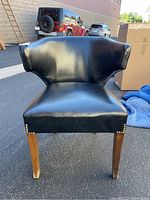 Front view of the black leather chair showing seat, backrest, and wooden legs.