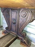 Carved end support showing scrollwork, central rectangular panel and rosette medallion
