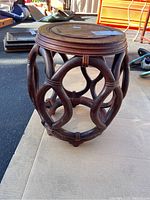 Full view of the wooden table showing curved wooden supports forming the open base, round top, and overall condition.