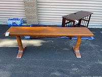 View of wooden bench from top showing rectangular seat and two pedestal legs with wide flat feet.