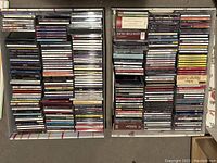 Overhead view of two trays filled with CD cases, showing variety of music genres and visible classical collections.