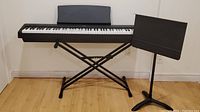 Kawai ES100 digital piano placed on adjustable X-style keyboard stand with music stand beside