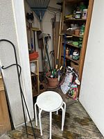 Overview of wooden shelf, white metal stool, metal hooks and extension cord