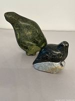 Two soapstone bird carvings, one green stone bird and one black seal bird on rock base