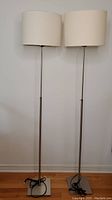 Two matching adjustable floor lamps side by side showing different heights and white textured drum shades.