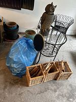 Wide angle view showing wicker baskets with wooden hangers, large blue bag of plastic hangers, metal wire plant stand, ceramic pots, and owl decoration