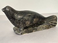 Front and side view of black stone seal sculpture showing shape and surface wear.