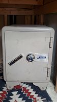 Front view of a grey Sentry safe with combination dial and horizontal handle, showing light scuffs and wear.