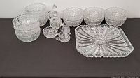Overview of all Bohemia crystal items including square plate, bowls, oil bottle, creamers, arranged on black surface