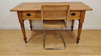 Full view of pine desk with cane-backed chair