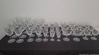 Overview of entire Waterford Lismore crystal stemware set on black surface.