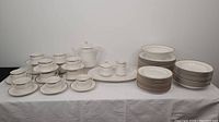 Full view of entire dish set including dinner plates, side plates, teacups and saucers, serving pieces with teapot, sugar bowl, creamer, serving bowl, and platter.