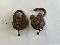 Two rusted iron Civil War era padlocks with original keys attached. One lock closed, one lock open.