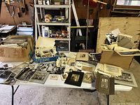 Overview of table covered with assorted loose prints, cabinet cards, group portraits in trays and boxes