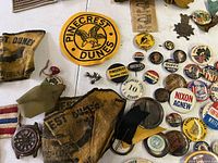 Overview photo showing a variety of Boy Scout patches, political pins, a red vintage wristwatch, and some cloth badges mainly related to Pinecrest Dunes.