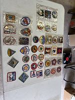 Overview of 41 Boy Scout patches arranged on a table with some inside plastic sleeves, showing multiple designs and colors.