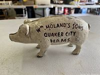 Side view of the antique piggy bank displaying the hand-painted advertising text Wm Moland's Sons Quaker City Hams.