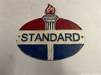 Front of cast iron Standard Oil sign showing the oval shape with red, white, and blue colors and torch design.