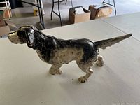 Side view of cast iron pointer dog door stop with black and white paint, showing wear and age.