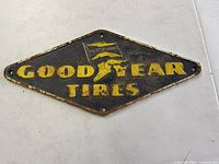 Front side of the diamond-shaped antique Goodyear Tires cast iron sign showing yellow raised lettering and logo on black background.
