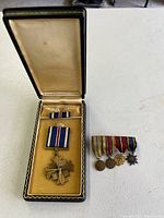 Photo of main Liberation of Philippines medal with ribbon bar in a fitted presentation case alongside four smaller mounted campaign medals with ribbons.