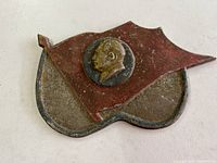 Overall view of the cast aluminium plaque shaped like a waving flag with Mao Zedong profile medallion in center.