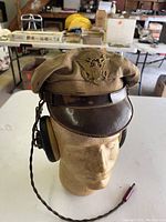 Front view of crusher cap with badge and attached headset on mannequin head