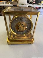 Front view of complete clock showing gold-tone brass case and silvered dial