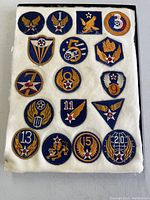 Full lot of 17 WWII era U.S. Army Air Corps patches displayed on white felt backing, showing various numbered air force insignia patches and emblematic designs.
