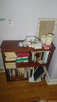 Front view of the wood bookcase filled with books and other items. Shows the size and condition of the bookcase.