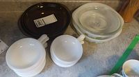 Pyrex Corning brown dish with lid, Glasbake milkglass dishes and soup bowls stacked showing size and condition.