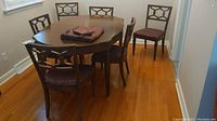 Wide view showing six wood framed dining chairs with fabric floral pattern cushions arranged around a dining table (table not included).