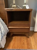 Front view of Gibbard wooden night stand showing open shelf and drawer with wooden handle, some scratches visible on surface.